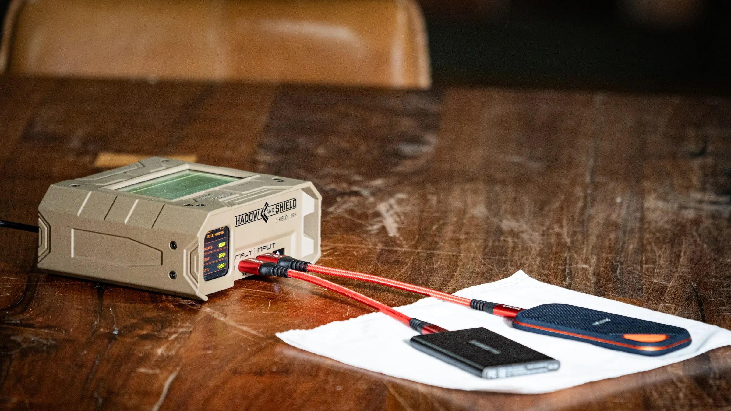 Tan Shield-399 unit connected to external drives on a wooden table