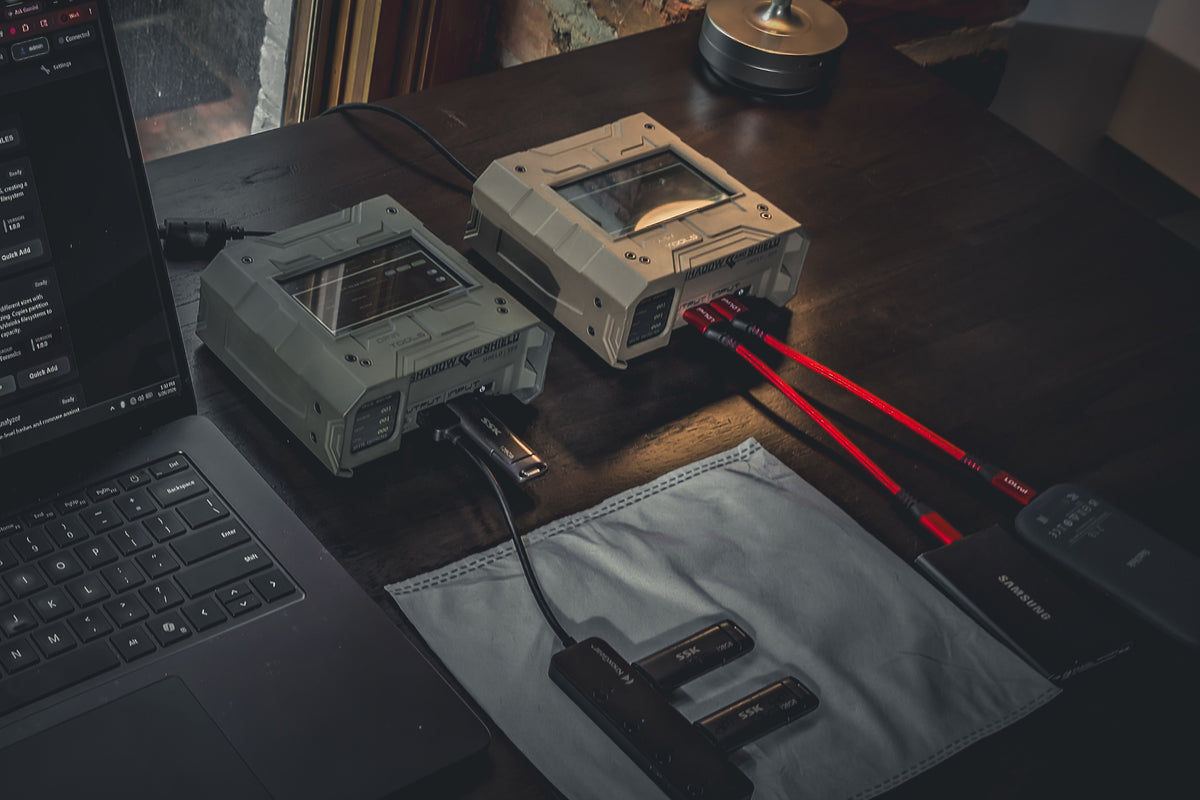 Two Shield-399 units beside a laptop and connected storage on a wooden desk by a window